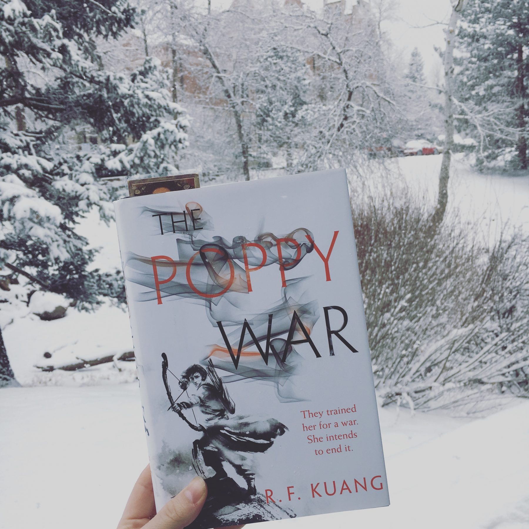 The Poppy War by RF Kuang against the backdrop of a snowy landscape